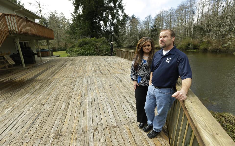 Darrin Moir, right, and his wife Leonor Moir, stand Monday, March 18, 2014 on the deck of their house, which is located along the Little Hoquiam River in Hoquiam, Wash. The Moirs currently pay about $1,700 annually for flood insurance, even though they say they have never had a major flooding incident since buying their home in 1996. Possible rate increases could up their premiums to more than $9,000 a year, which they say could prevent them from eventually selling their home. (AP Photo/Ted S. Warren)