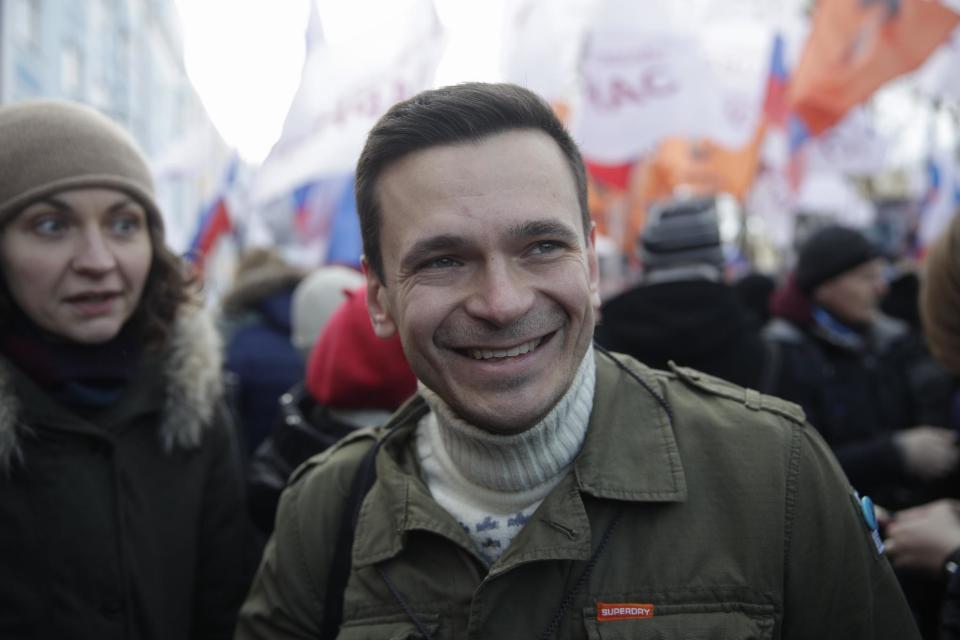 Russian opposition activist Ilya Yashin smiles as he takes part in a march in memory of opposition leader Boris Nemtsov in Moscow, Russia, Sunday, Feb. 26, 2017. Thousands of Russians take to the streets of downtown Moscow to mark two years since Nemtsov was gunned down outside the Kremlin. The poster reads: We shall overcome! (AP Photo/Pavel Golovkin)