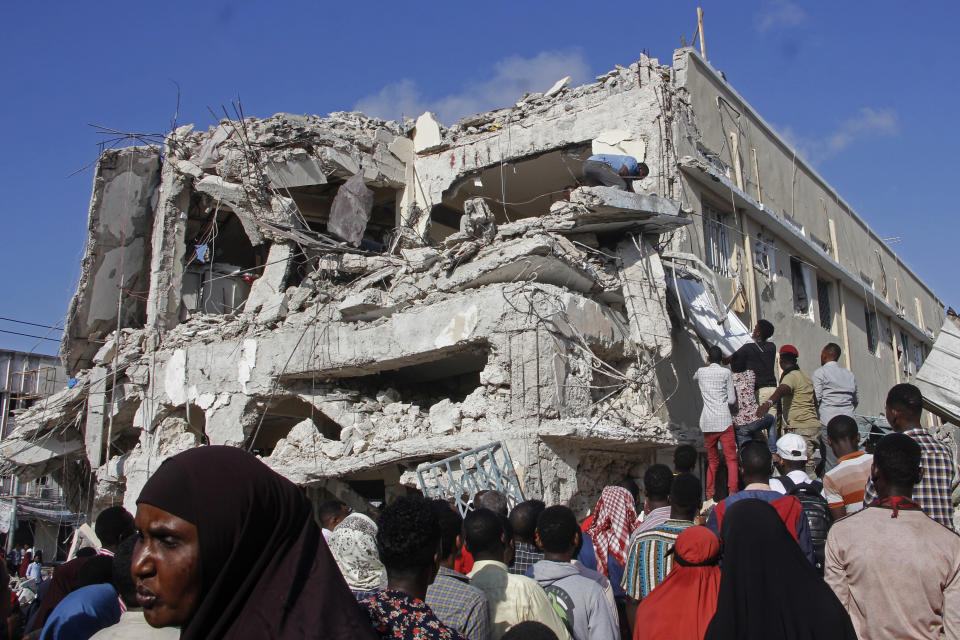 Relatives wait for bodies to be removed from the destruction at the scene, a day after a double car bomb attack at a busy junction in Mogadishu, Somalia, Sunday, Oct. 30, 2022. (AP Photo/Farah Abdi Warsameh)