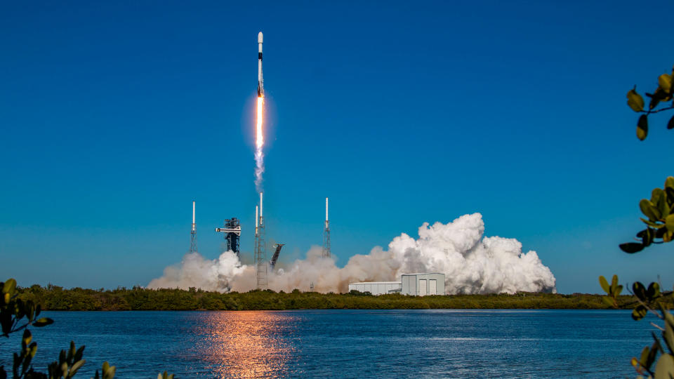 a black-and-white spacex falcon 9 rocket launches into a blue sky.