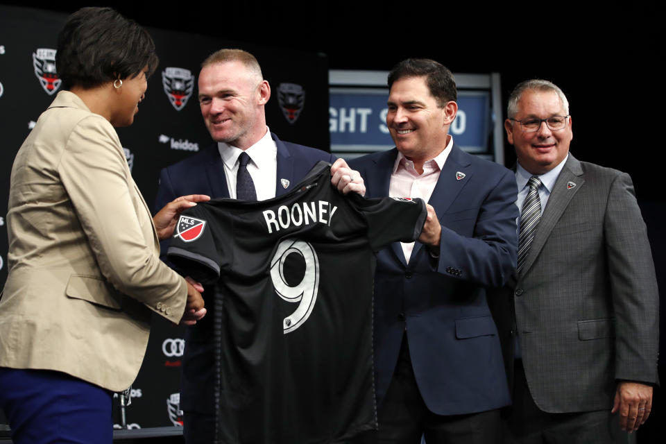 FILE - In this Monday, July 2, 2018, file photo, District of Columbia Mayor Muriel Bowser, left, shakes hands with English soccer star Wayne Rooney, as he holds up his new jersey next to MLS team D.C. United Managing Partner and CEO Jason Levien, and Dave Kasper, general manager and vice president of soccer operations, right, during a news conference announcing Rooney's signing with the club, at the Newseum in Washington. Rooney and his American club are headed to the Major League Soccer playoffs. (AP Photo/Jacquelyn Martin, File)