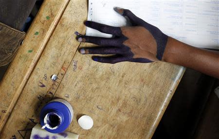 An official from Madagascar's Commission Electorale Nationale Independante pour la Transition (CENI-T) is seen with his hand stained with electoral ink as he processes voters at a polling centre in the capital Antananarivo, December 20, 2013. REUTERS/Thomas Mukoya