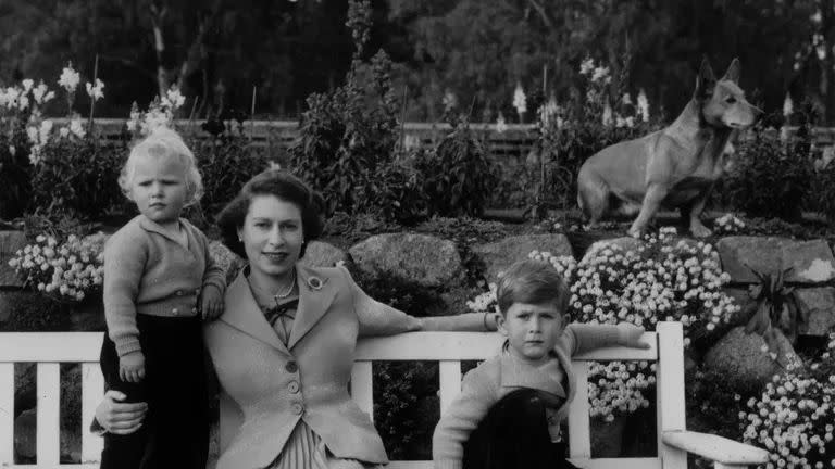 queen elizabeth sitting with her children, charles and anne and a royal corgi