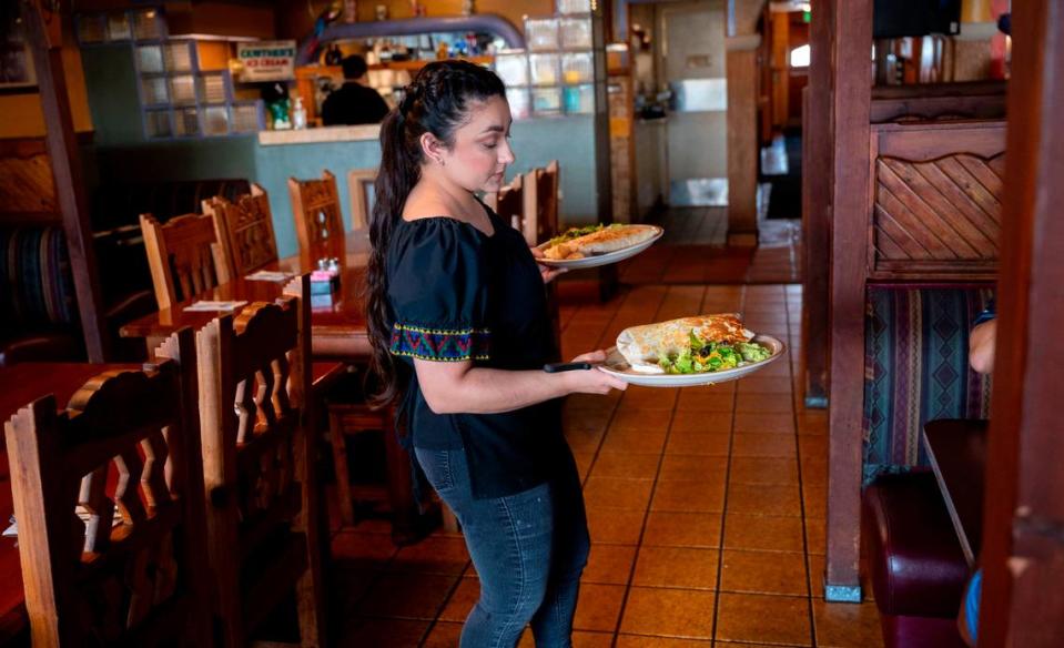 Lexi Villalpando serves a table burrito grandes at Caballo Blanco restaurant on Friday.