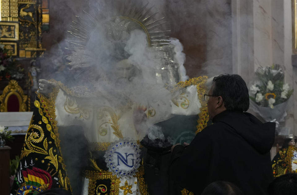 A priest releases incense after dressing the statue of "Jesus del Gran Poder" or Lord of Great Power, at the "Jesus del Gran Poder" church in La Paz, Bolivia, Thursday, June 1, 2023. Thousands of dancers and musicians will parade on Saturday to show their devotion and thank God and for the year's blessings. (AP Photo/Juan Karita)