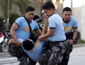 Police carry a colleague who collapsed while retrieving bodies of workers killed during a fire at a slipper factory in Valenzuela, Metro Manila in the Philippines May 14, 2015. A fire at a factory making rubber slippers killed 31 workers in the Philippine capital on Wednesday, and dozens were missing and feared dead, officials said. REUTERS/Erik De Castro