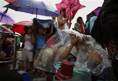 Residents shelter from the rain as they wait to get onto a military plane during an evacuation at Tacloban airport in the Typhoon Haiyan devastated city, November 16, 2013. Survivors began rebuilding homes destroyed by Haiyan, one of the world's most powerful typhoons, and emergency supplies flowed into ravaged Philippine islands, as the United Nations more than doubled its estimate of people made homeless to nearly two million. REUTERS/Bobby Yip