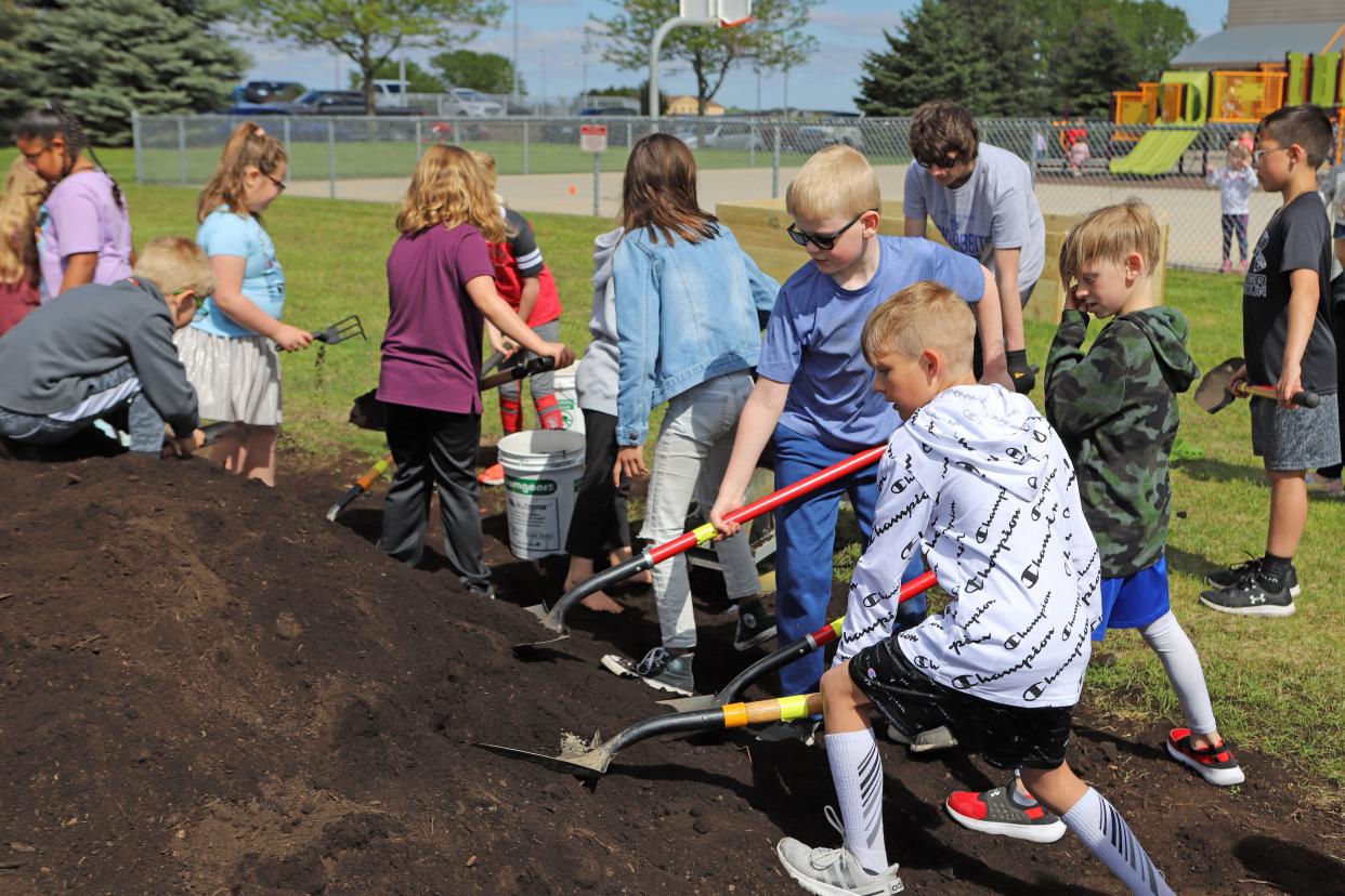 Children at EmBe's childcare center move compost to use in the new teaching gardens on Thursday, May 26.