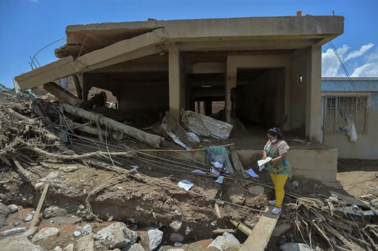 A Colombian woman looks at a child's notebook in the midst of rubble left by mudslides in Mocoa, Putumayo department, on April 4, 2017