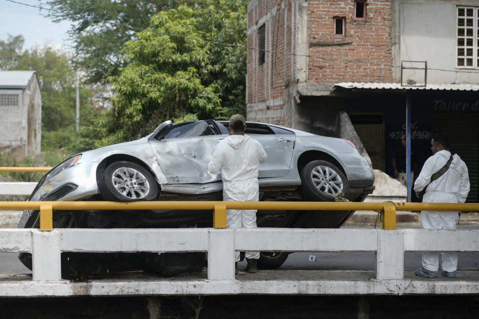 Forensic medical examiners work at the scene where an unidentified man was killed in Apatzingan, Mexico, Sunday, July 2, 2023. Apatzingan, the regional hub where the area's agricultural products are traded, gunmen carjacked a family, took their auto at gunpoint and used it to shoot another driver to death just a few blocks away. (AP Photo/Eduardo Verdugo)