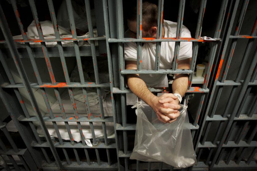 103250.ME.1011.jails.BRV -- An inmate leans out the bars of his cell in a one-prisoner per cell block. Crowded conditions at the Men's Central Jail in downtown Los Angeles sometimes forces inmates to sleep on the floor when the population swells above maximum capacity. The Sheriff contends the State of California has the responsibility to pick up inmates who are discharged from courts to begin serving their sentences in state prison and thereby help relieve overcrowding. Los Angeles Times photo by Brian Vander Brug