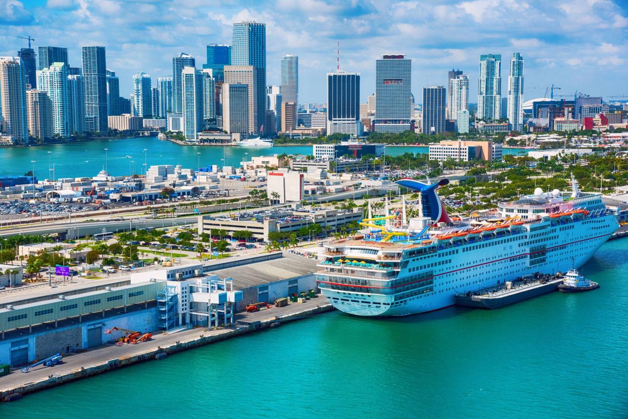 Miami, United States - March 9, 2017:  A large Carnival Cruiseline ship docked at the terminal with downtown Miami, Florida rising in the background.