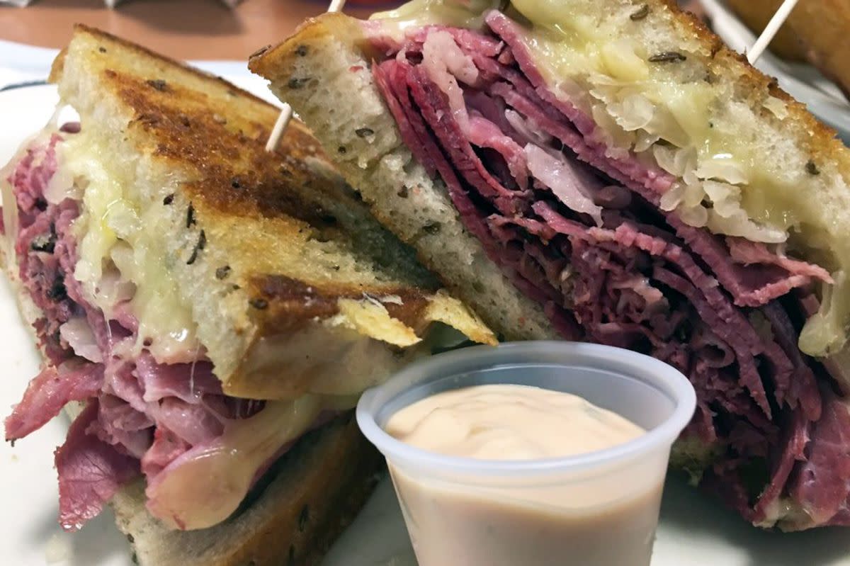 Closeup of Corned Beef Sandwich with a small cup of Thousand Island dipping sauce on a ceramic plate, Rein's New York Style Deli, Vernon, Connecticut, on a table