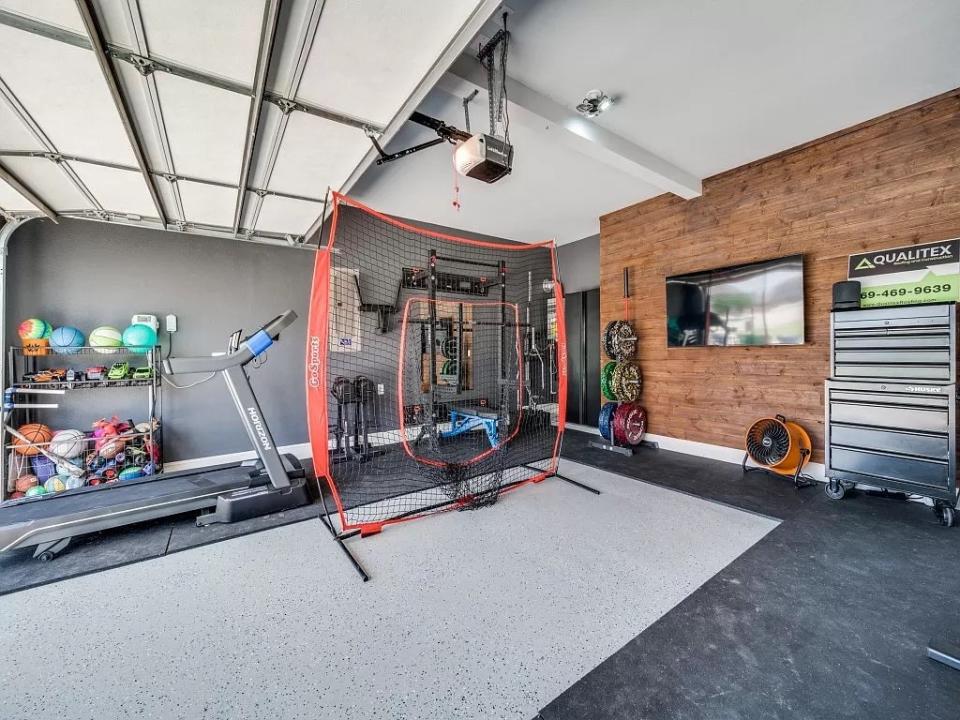 Garage converted into a home gym, with treadmill, sports balls, and sports net inside.
