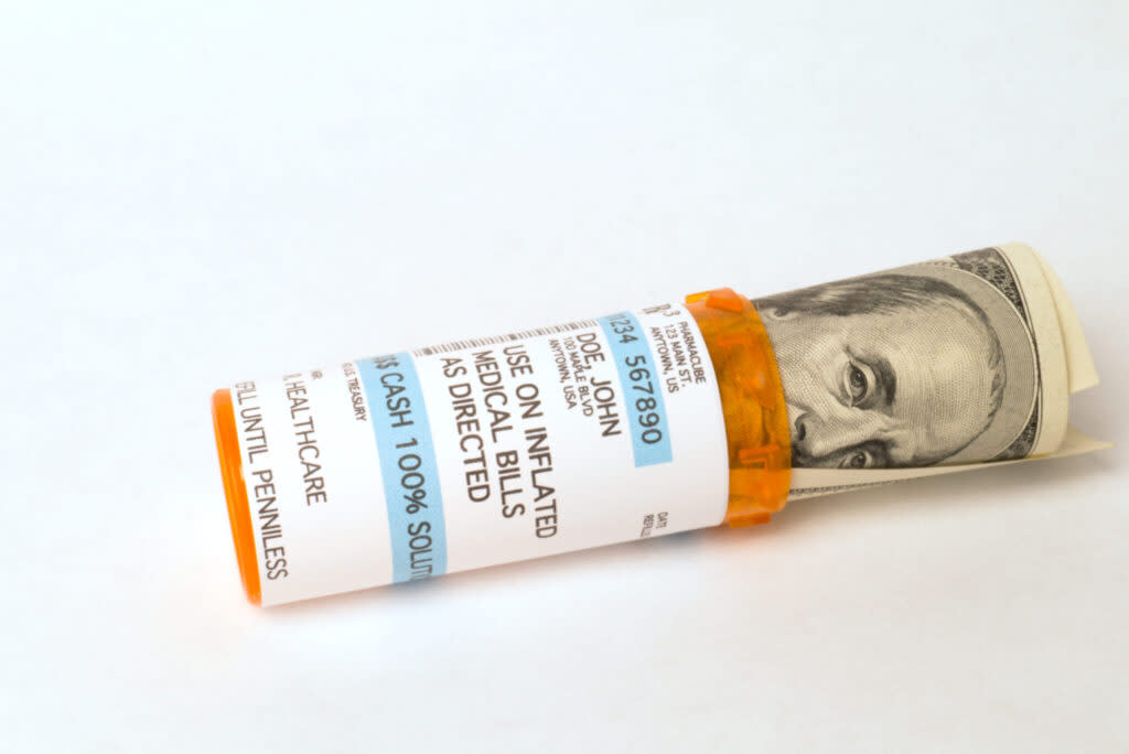 Jar for prescription drugs stuffed with hundred dollar bill representing high cost health care