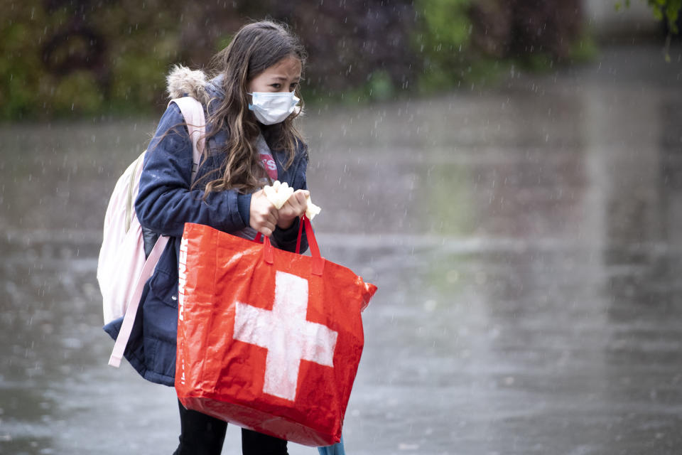 FILE - A pupil wearing a protective mask arrives at a primary school Etablissement Primaire de l'ecole vaudoise, in Morges, Switzerland, 11 May 2020. Classroom teaching at primary and lower secondary schools will again be permitted. Switzerland is facing an exponential rise in coronavirus cases. But its federal government, hasn't responded with new lockdown measures. Experts say that's because the government's anti-COVID policies face a crucial test at the ballot box. On Sunday Nov. 28, 2021, Swiss voters will cast ballots on a ‚COVID-19 law' that has unlocked billions of Swiss francs in aid for workers and businesses hit by the pandemic. (Laurent Gillieron/Keystone via AP, File)