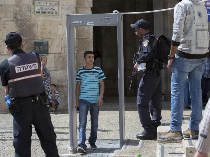 Israelische Polizisten lassen einen jungen Palästinenser durch einen Metalldetektor gehen. Foto: Jim Hollander