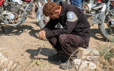 A member of the Syrian civil defence volunteers mourns his comrades - Credit: AFP PHOTO / OMAR HAJ KADOUR