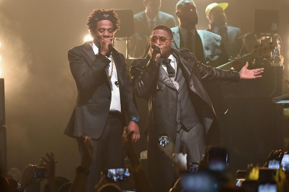 Jay-Z and Nas wearing black suits performing on stage 