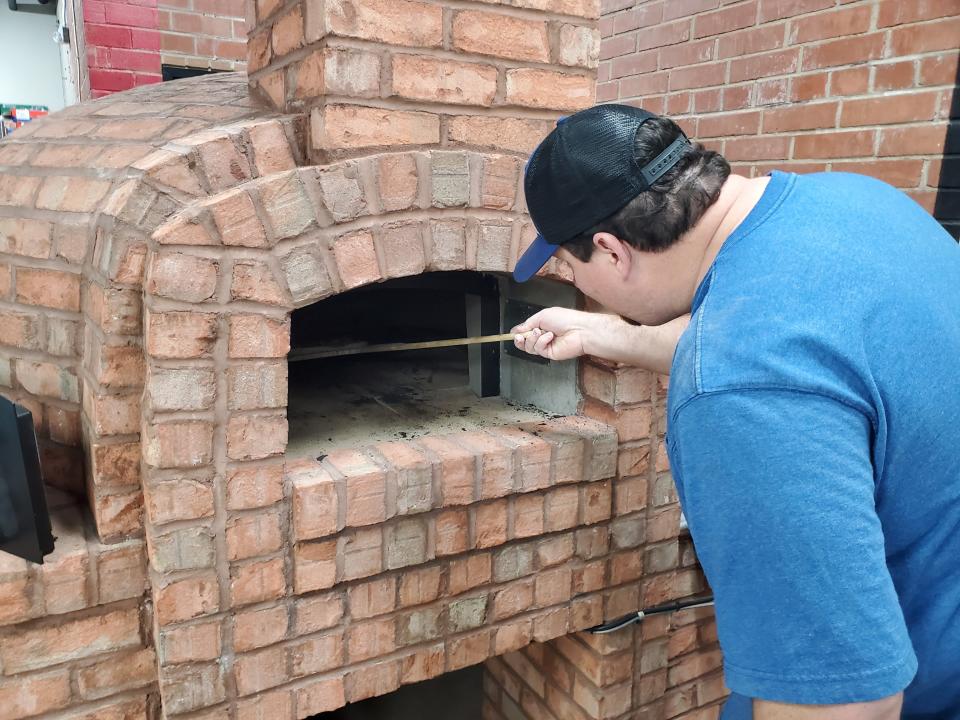 Tyler Prevatte, one of the owners of Pour Folk Provisions, located inside Goose and the Monkey Brewhouse, turns a pizza inside the eatery's new brick oven.