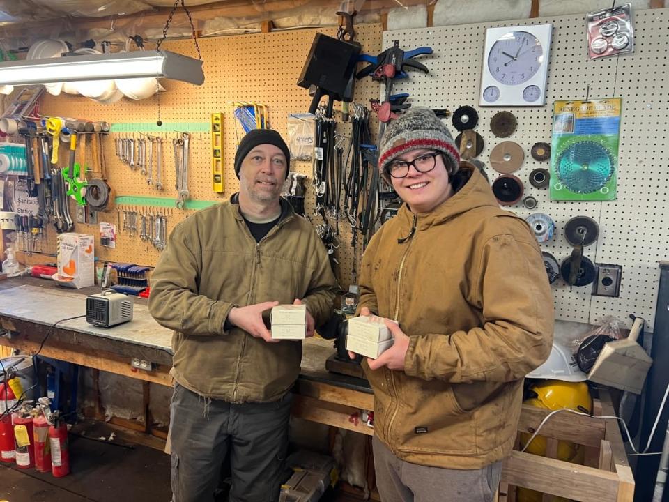 Joel Letendre, left, and Noah Beaton of Tea Creek Farm hold the boxes of microfilm from William Beynon they found while cleaning out the farm's shop.  (Jacob Beaton - image credit)