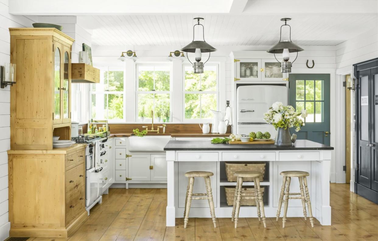 airy kitchen with antique style lighting, a large island with built in storage, and butcher block countertops