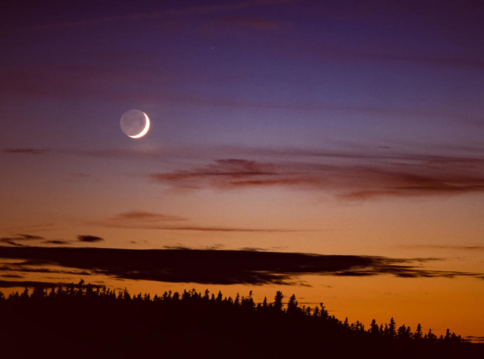 Earthshine, or the Da Vinci glow, reflects off of a crescent moon setting in Canada. / Credit: / Getty Images