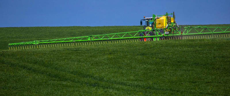 Farming systems around the world are affecting groundwater and in some cases, increasing desertification. Here, a tractor pulls a sprayer with wide booms and spreads fertilizer and pesticides on a grain field. Jens Büttner/dpa