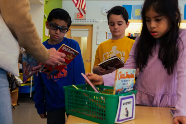 Third grade teacher Rebecca Fox suggests books to her students at Hamilton Avenue School in Greenwich. She chooses them based on their reading level and taste. (Shahrzad Rasekh/CT Mirror)
