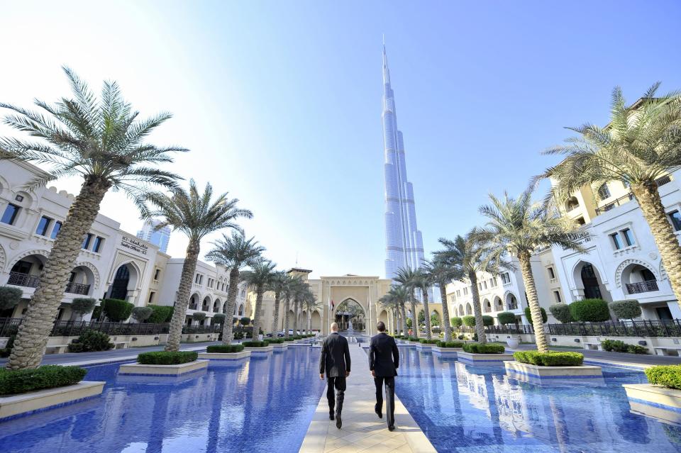 Two businessmen walking in the old town at the bottom of the megatall skyscraper Burj Khalifa in Dubai (United Arab Emirates).