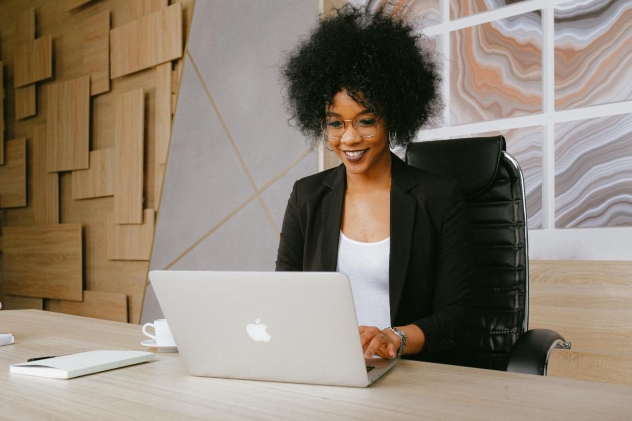 Black woman smiling with black blazer wearing glasses typing on computer. Newegg Fantastech Deals