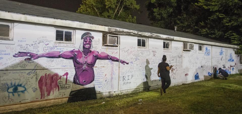 A person reads the personal messages written on the wall next to the convenience store where Alton Sterling was shot and killed.