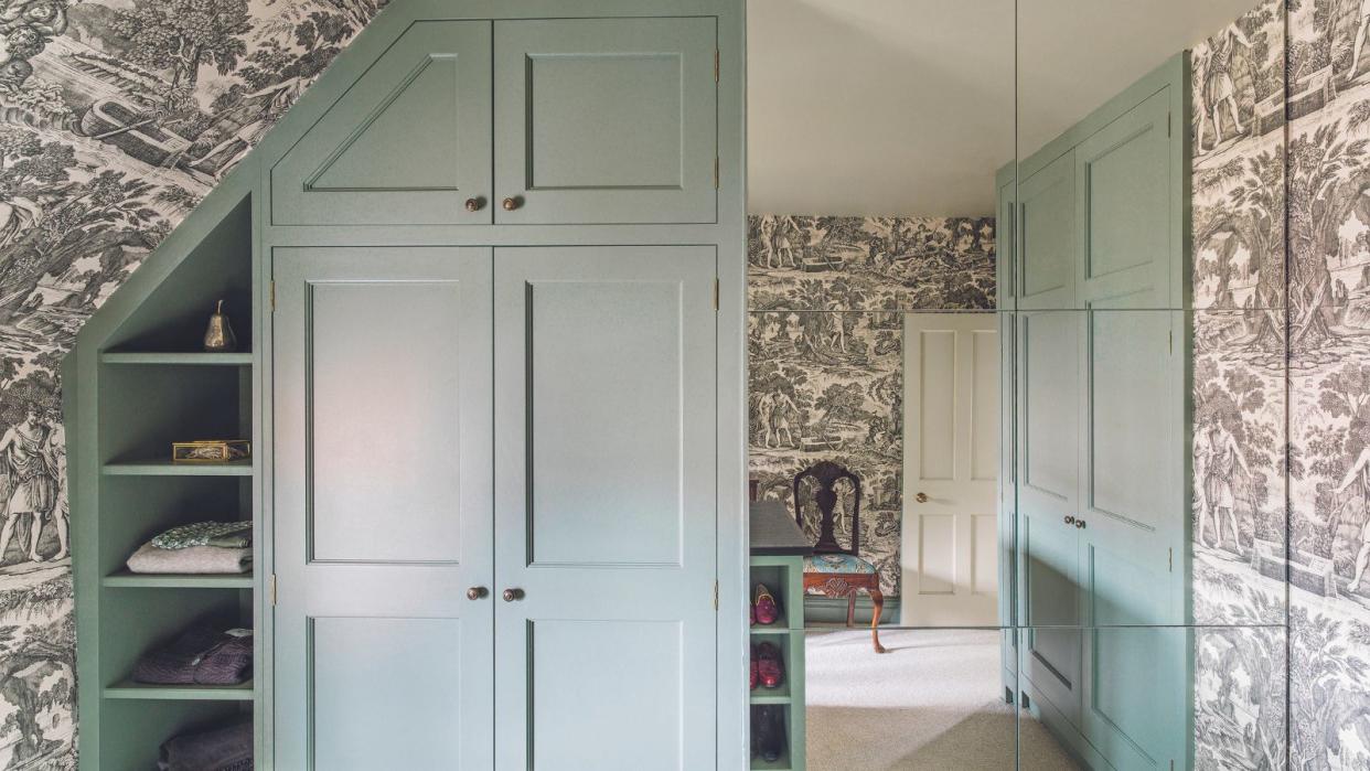  Dressing room with built-in cupboards and mirror tiles on one wall. Grey toile wallpaper. 