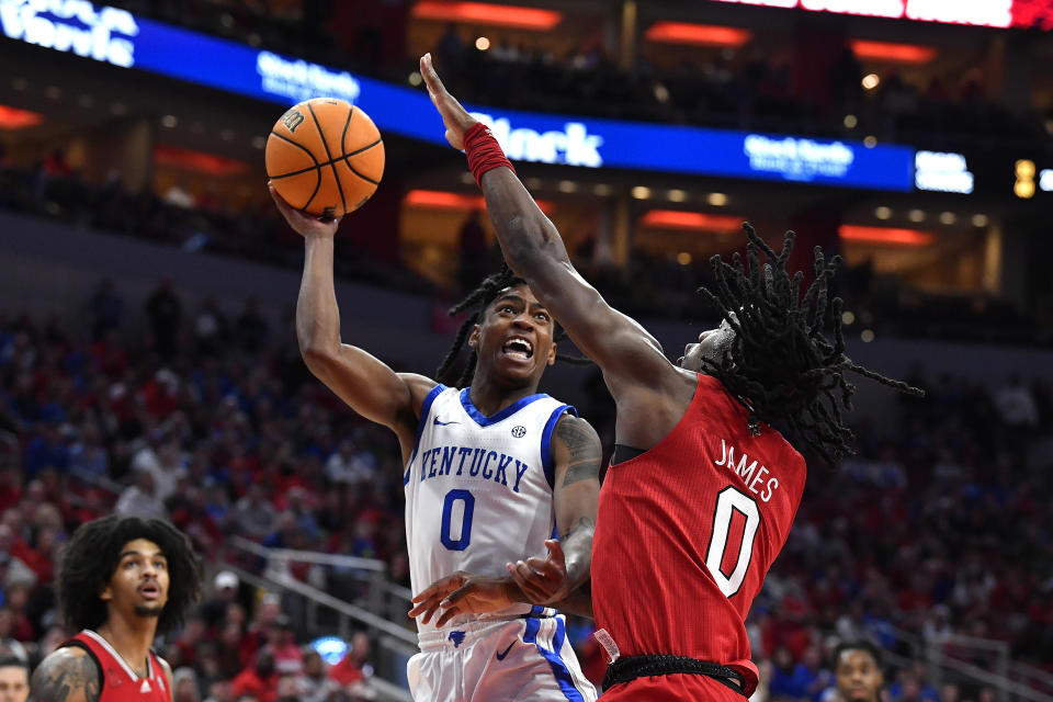 Kentucky guard Rob Dillingham, center, shoots over Louisville guard Mike James, right, during the first half of an NCAA college basketball game in Louisville, Ky., Thursday, Dec. 21, 2023. (AP Photo/Timothy D. Easley)