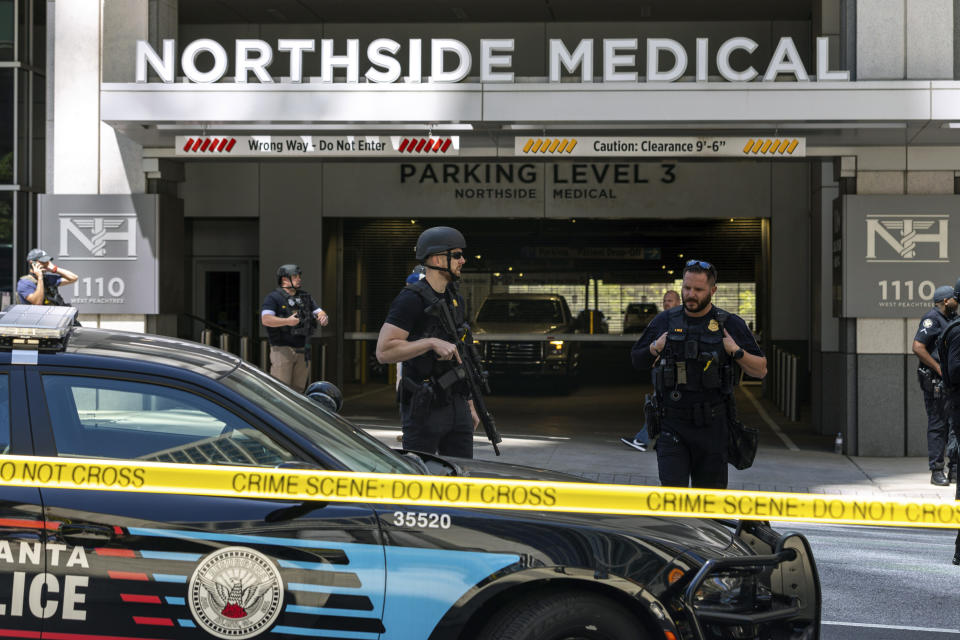 Law enforcement officers stand Northside Hospital Midtown medical office building, where five people were shot, Wednesday, May 3, 2023, in Atlanta. Authorities swarmed the city’s bustling midtown neighborhood in search of the 24-year-old suspect. (Arvin Temkar/Atlanta Journal-Constitution via AP)