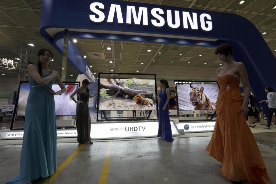 FILE - In this May 21, 2013 file photo, South Korean models wait for the start of reception near Samsung Electronics' 85-inch Ultra High Definition (UHD) TVs during the World IT Show in Seoul, South Korea. Samsung Electronics Co., which is preparing for the global launch of the Galaxy S5 smartphone on April 11, 2014, said it is making “concentrated efforts” to ensure its communications around the world respectfully portray women. Some of its promotions and corporate events in the past year were criticized as sexist and demeaning. The advertising of LG Electronics Inc. has also been under scrutiny in South Korea and abroad for its portrayal of women. (AP Photo/Lee Jin-man, File)