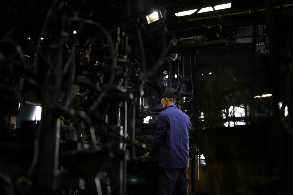 A worker inspects a machine in the factory of the French glassmaker Duralex, in La Chapelle Saint-Mesmin, central France, Wednesday, Sept. 7, 2022. Iconic French tableware brand Duralex is joining a growing array of European firms that are reducing and halting production because of soaring energy costs. (AP Photo/Thibault Camus)