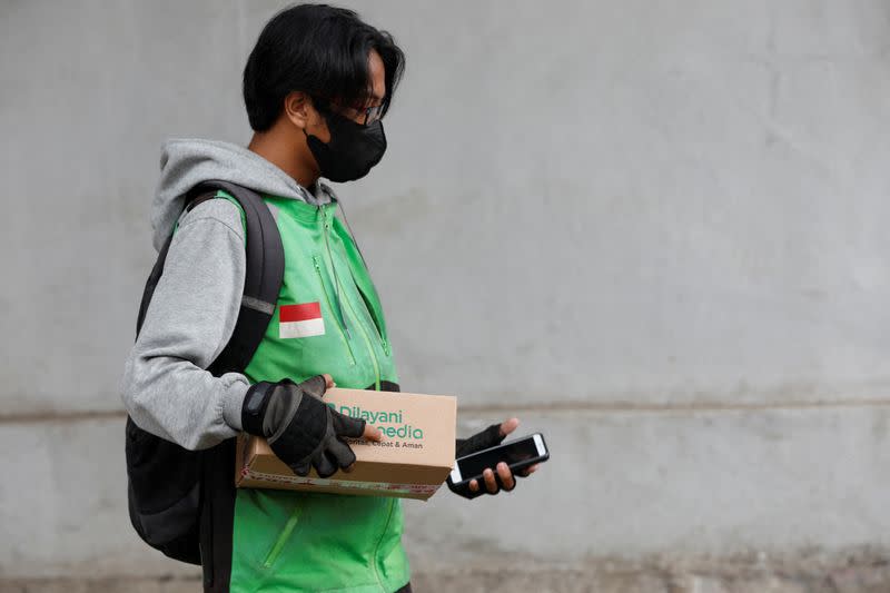 FILE PHOTO: An online motorbike taxi driver carries a good at Goto's e-commerce unit Tokopedia's warehouse in Jakarta