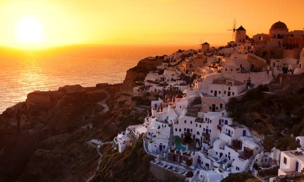 Sunset over whitewashed village on volcanic rim of caldera.