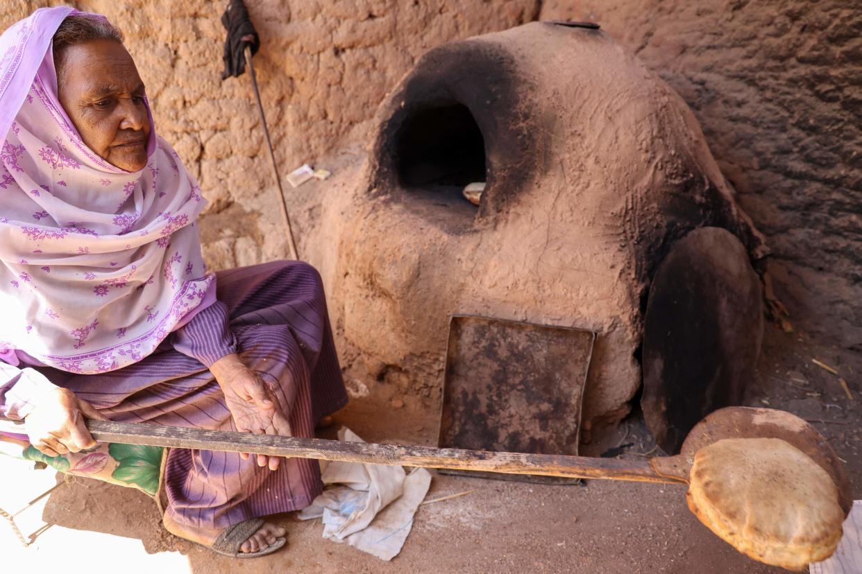 Local resident Naamat Jabal Sayyid Hasan, 75, bakes bread in a mud hut as she does daily to offer to people fleeing war-torn Sudan (AFP via Getty Images)