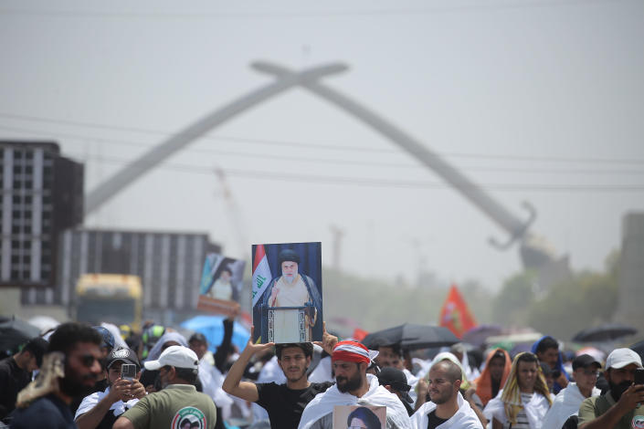 Followers of Shiite cleric Muqtada al-Sadr holds his photo during an open-air Friday prayers at Grand Festivities Square within the Green Zone, in Baghdad, Iraq, Friday, Aug. 5, 2022. (AP Photo/Anmar Khalil)