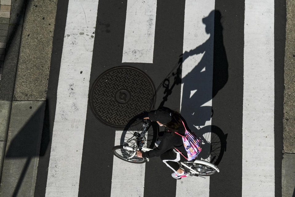 Una persona en bicicleta por una calle en Tokio, Japón, durante los días de emergencia por el coronavirus, el 26 de abril de 2021. (AP Foto/Kiichiro Sato)