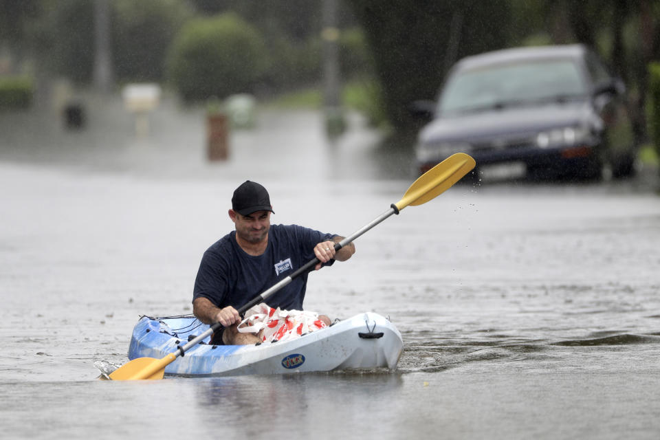 Ben Deller paddles down a flooded street in a kayak loaded with groceries for his family in Windsor, northwest of Sydney, New South Wales, Australia, Tuesday, March 23, 2021. Hundreds of people have been rescued from floodwaters that have isolated dozens of towns in Australia's most populous state New South Wales and forced thousands to evacuate their homes as record rain continues to inundate the country's east coast. (AP Photo/Rick Rycroft)