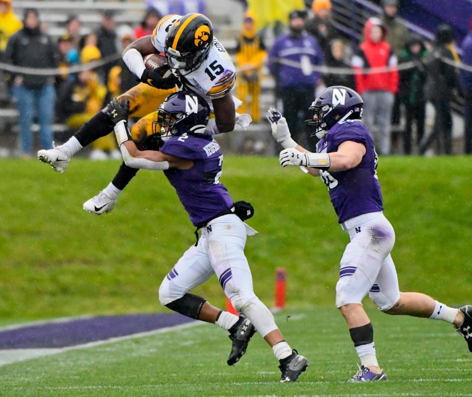 Oct 26, 2019; Evanston, IL, USA; Iowa Hawkeyes running back Tyler Goodson (15) leaps over Northwestern Wildcats defensive back Greg Newsome II (2) and Northwestern Wildcats linebacker Chris Bergin (28) during the second half at Ryan Field. Mandatory Credit: Matt Marton-USA TODAY Sports