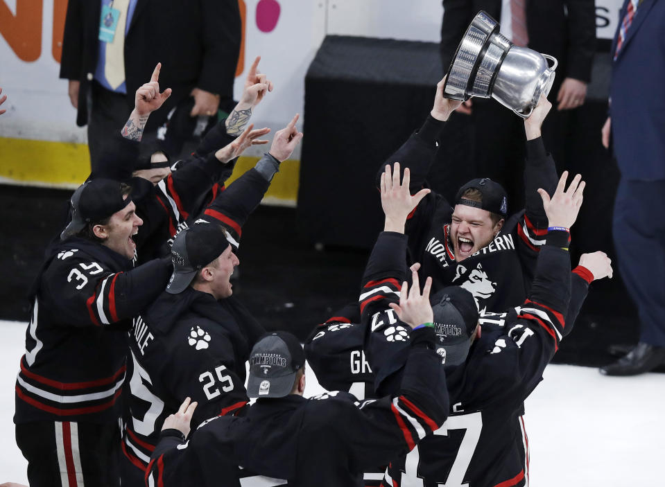 Northeastern defenseman Eric Williams, right, hoists the championship trophy after defeating Boston College 4-2 in the NCAA hockey Beanpot tournament final game in Boston, Monday, Feb. 11, 2019. Northeastern won 4-2. (AP Photo/Charles Krupa)