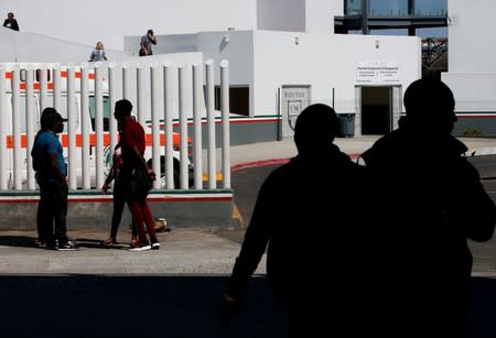 People wait to apply for asylum in the United States outside the El Chaparral border in Tijuana