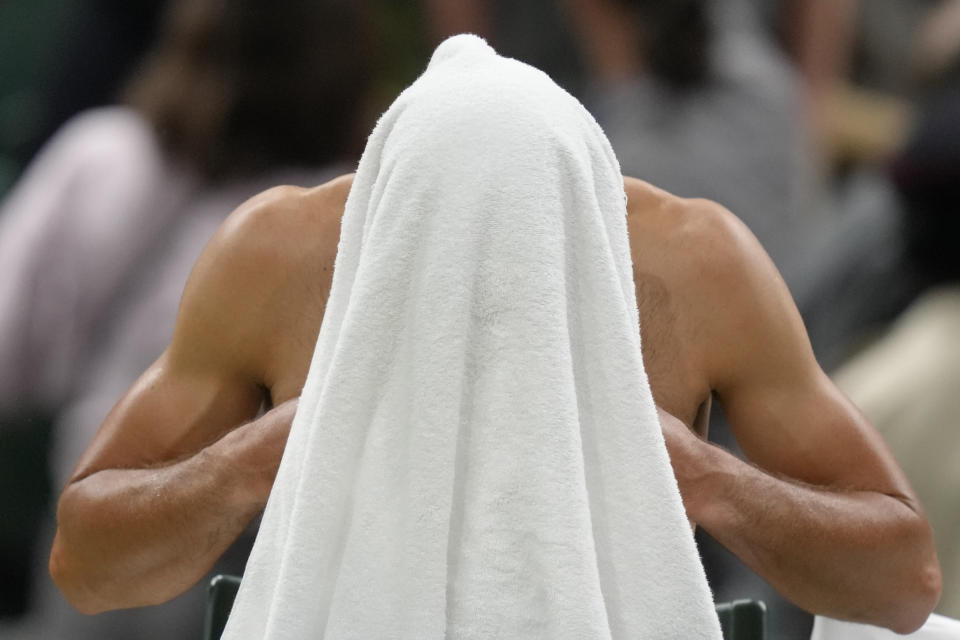 Serbia's Novak Djokovic changes his shirt after the second set against Tim van Rijthoven of the Netherlands during a men's fourth round singles match on day seven of the Wimbledon tennis championships in London, Sunday, July 3, 2022.(AP Photo/Kirsty Wigglesworth)