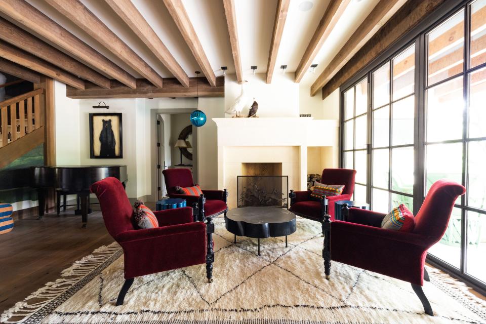 Their more formal living space features four Ralph Lauren armchairs decorated with antique Swedish pillows from Howe London, two ceramic cocktail tables from Bzippy in Los Angeles, and a coffee table with custom brass inlay from Sawkille Co. in upstate New York. The blue-and-yellow striped ottoman (glimpsed far left) was made by Davidson out of a dhurrie from the Padaleckis’ former home in Los Angeles. The piano belonged to Genevieve’s mother.