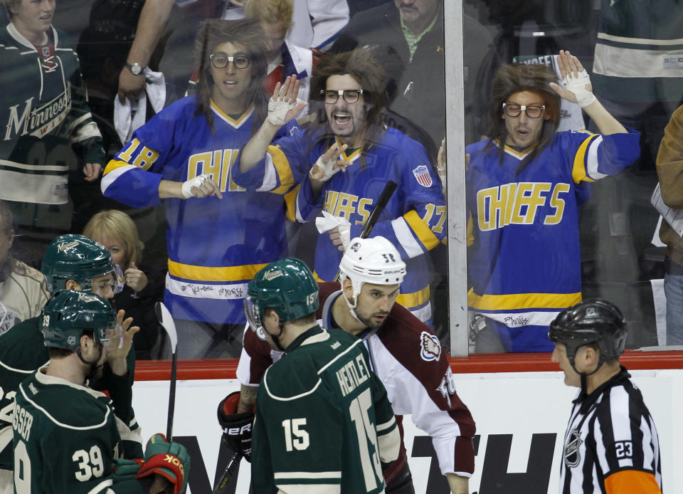 FILE - In this April 21, 2014, file photo, fans dressed as the Hanson Brothers from the movie "Slap Shot" yell at players and referees as Minnesota Wild defenseman Clayton Stoner and Colorado Avalanche center Brad Malone are assessed penalties during the first period of Game 3 of an NHL hockey first-round playoff series in St. Paul, Minn. "Slap Shot" was No. 5 in The Associated Press’ Top 25 favorite sports movies poll. (AP Photo/Ann Heisenfelt, File)