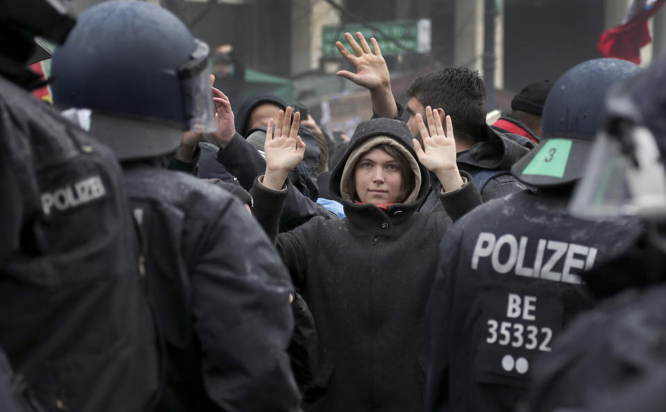 A protestor lifts her hands as police officers block a road between the Brandenburg Gate and the Reichstag building, home of the German federal parliament, as people attend a protest rally in front of the Brandenburg Gate in Berlin, Germany, Wednesday, Nov. 18, 2020 against the coronavirus restrictions in Germany. Police in Berlin have requested thousands of reinforcements from other parts of Germany to cope with planned protests by people opposed to coronavirus restrictions. (AP Photo/Michael Sohn)